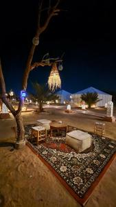 a park with a table and a tree at night at Unique Luxury Camp in Merzouga