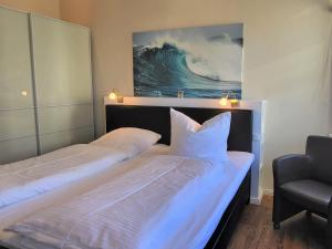 a bedroom with two beds and a chair and a painting at Hotel Hubertusburg in Kühlungsborn