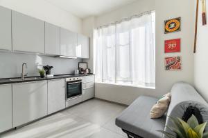 a kitchen with white cabinets and a couch in a room at Baroni C - FREE private parking-wi- fi and A-C in Gerenzano