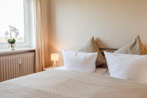 a bedroom with a bed with white pillows and a window at Haus Uthlande Uthlande Whg 49 Inselauszeit in Wyk auf Föhr +22 photos