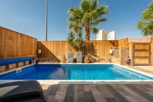 a swimming pool with a wooden fence and a palm tree at Perfect Family Vacation-Private Pool Eilat in Eilat