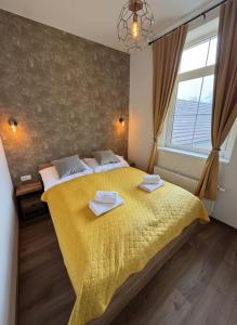a bedroom with a yellow bed with towels on it at Samaya Apartment in Litoměřice
