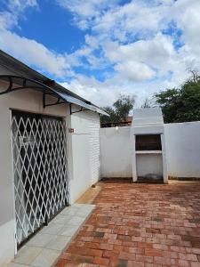 a white house with a gate and a brick driveway at Lalapanzi Accommodation in Vosburg +4 photos