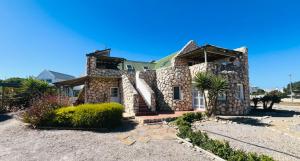 a stone house with a palm tree in front of it at See-Rus Self Catering Seaside Accommodation in Jacobs Bay