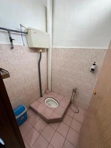 a bathroom with a toilet in a pink tiled floor at Santai DPermai Homestay in Selama