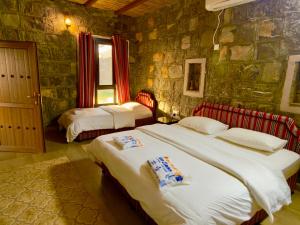 a bedroom with two beds and a stone wall at Jebel shams Sky in Misfāh