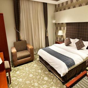 a hotel room with a bed and a chair at Banan Ruz - شقق مخدومة in Hafr Al Baten