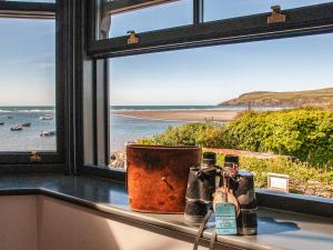 Una ventana con botellas sobre un mostrador que da a una playa en Parrog Point, en Newport