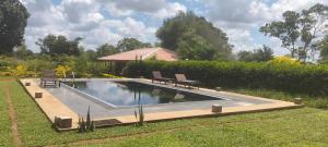 a swimming pool with two chairs in a yard at Tiara Elephant Lodge in Habarana