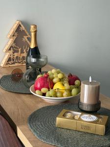 a table with a plate of fruit and a bottle of wine at Cozy studio near the park with huge verandah. in Veliko Tŭrnovo