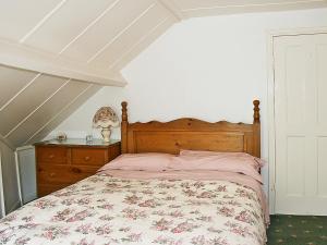 a bedroom with a bed with a floral bedspread and a dresser at Flagstaff Cottage in Robin Hood's Bay