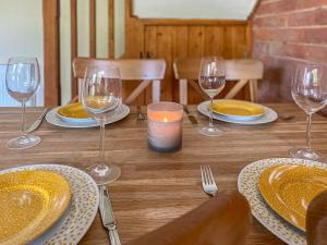 Una mesa de madera con platos y copas de vino encima. en The Old Carthouse, en Abbots Bromley