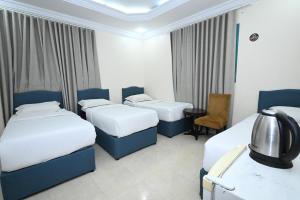 a hotel room with three beds and a chair at بيت سلسبيل in Al Madinah