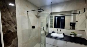 une salle de bain avec un lavabo et une douche en verre dans l'établissement Apartamenty Graniczna 1, à Rzeszów