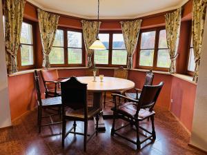a dining room with a table and chairs and windows at VILLA SEEBERG - by "Schloss Gessenberg" luxurious vacation home with lake and mountain views, suitable for families and friends in Petting