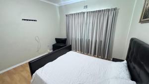 une chambre avec un lit et une chaise dedans dans l'établissement SVI Suits, à Bloemfontein