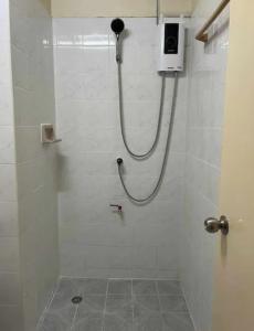 eine Dusche mit Schlauch in einem weiß gefliesten Badezimmer in der Unterkunft Foodie heaven in Thonhuri