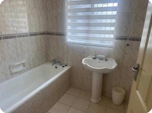 une salle de bain avec une baignoire et un lavabo et une baignoire dans l'établissement SVI Suits, à Bloemfontein 13 autres photos