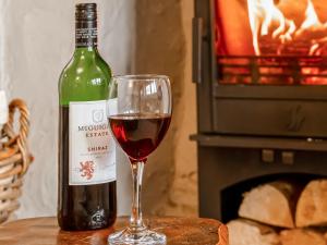 a glass of red wine next to a bottle of wine at Lodge Farm Cottage in Haworth