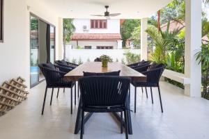 an outdoor dining room with a wooden table and chairs at Charming 3BR villa with Private pool in Bangrak Beach