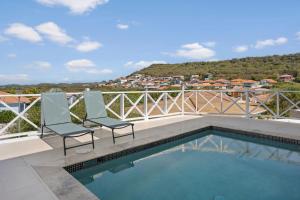 a swimming pool on a balcony with two chairs at Luxe Villa Met Panoramisch Zicht En Privzwembad in Willemstad