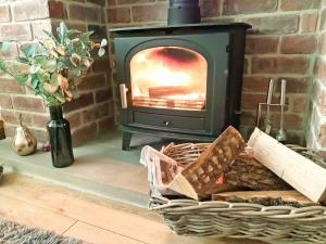 a fireplace with a wood stove and a basket of bread at Keepsake View in Two Dales +27 photos