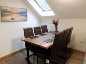 a dining room table with chairs and a vase of flowers at Ysgubor Uchaf - 29517 in Fairbourne