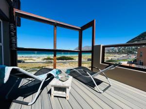 a rocking chair on a deck with a view of the ocean at the Lighthouse Beachroom in Cape Town