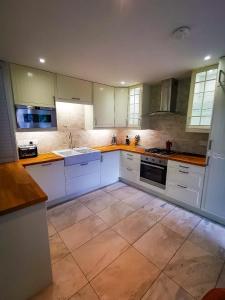 eine Küche mit weißen Schränken und einem Fliesenboden in der Unterkunft Rosemarinus a Peaceful 4Bed 3Bath Townhouse Ballycastle in Ballycastle