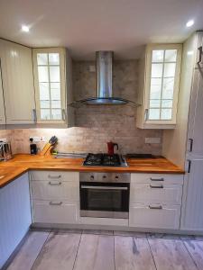 eine Küche mit weißen Schränken und einem Herd mit Backofen in der Unterkunft Rosemarinus a Peaceful 4Bed 3Bath Townhouse Ballycastle in Ballycastle