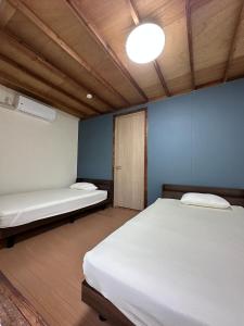 1 Schlafzimmer mit 2 Betten und einer Leuchte in der Unterkunft 一棟貸し Cottage CASA 屋久島空港近く利便性良し 森に囲まれ静かな一軒家 in Yakushima