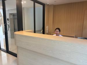 a woman sitting at a counter in an office at Luna Resident in Ban Bang Phai