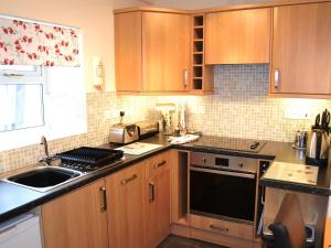 a kitchen with wooden cabinets and a sink at Uncle's Cottage in Keswick