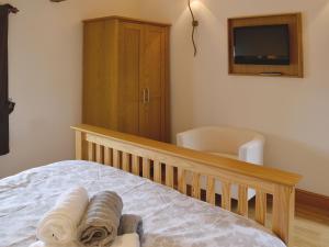 1 dormitorio con cuna, TV y silla en The Top Barn, en Coedana