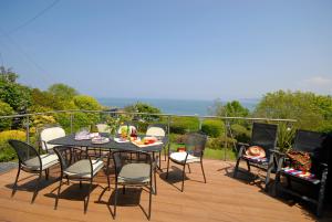 une table et des chaises sur une terrasse avec une table et un barbecue dans l'établissement Seascape, à New Quay