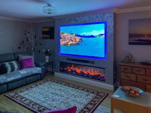 a living room with a fireplace and a tv on a wall at Rivendell Lodge - Cottage in East Winch