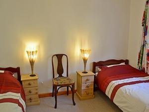 a bedroom with two beds and a chair and two lamps at Ponsgwedhen in Coverack +14 photos