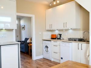 a kitchen with white cabinets and a washer and dryer at 14 Greta Villas in Keswick