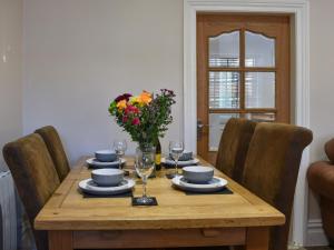 a wooden table with a vase of flowers on it at Meadow View Cottage in Stanhope