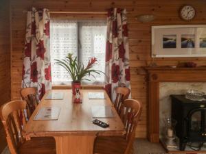 a dining room with a wooden table and a fireplace at Fell View Lodge in Keswick