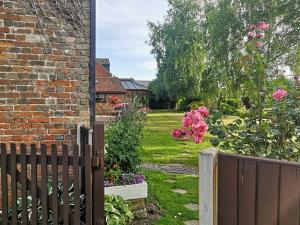 a garden with a wooden fence and flowers at Elm Barn View in Freethorpe