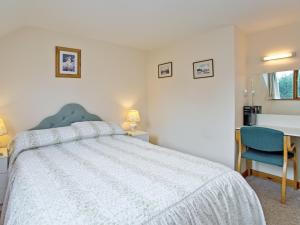 une chambre avec un lit et une chaise bleue dans l'établissement Coot Cottage, à Dilham 6 autres photos