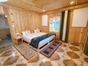 a bedroom with a bed in a room with wooden walls at Tirthan Majestic View Homestay in Kulu