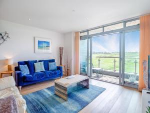 a living room with a blue couch and a large window at 7 Cribbar in Newquay