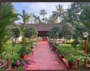 a pathway in a garden with flowers and palm trees at Rice Village Home Stay in Alleppey