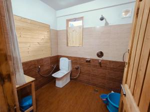 a bathroom with a toilet and a window in it at Tirthan Majestic View Homestay in Kulu