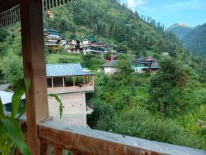 a view from a balcony of a village in the mountains at Tirthan Majestic View Homestay in Kulu