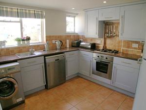 a kitchen with white cabinets and stainless steel appliances at Waters Edge in Instow