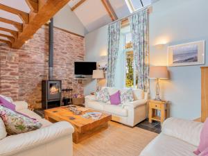 a living room with two couches and a fireplace at The Old Cowshed in Saint Ishmaels