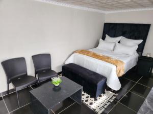 a bedroom with a bed and two chairs at WinHaven Guest House in Randfontein